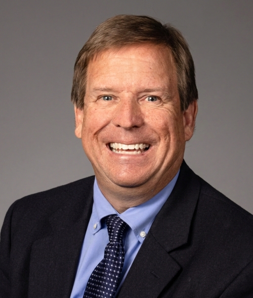 Smiling man of ~55 years old in tie and suit jacket with light brown hair