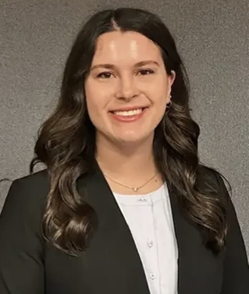 a young woman with long curly dark hair wearing a black blazer and white blouse