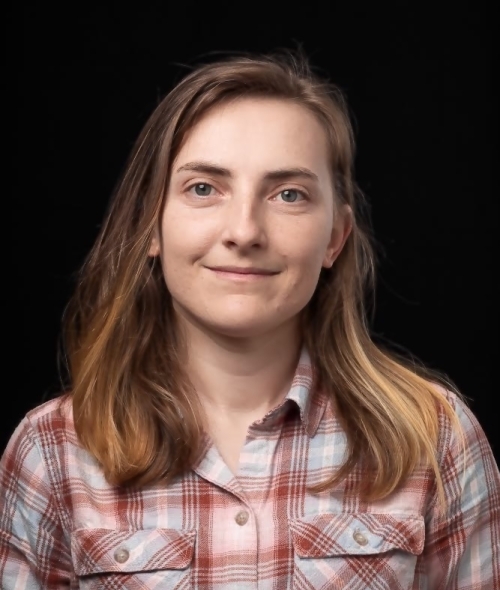 a young woman wearing a flannel shirt on a black background