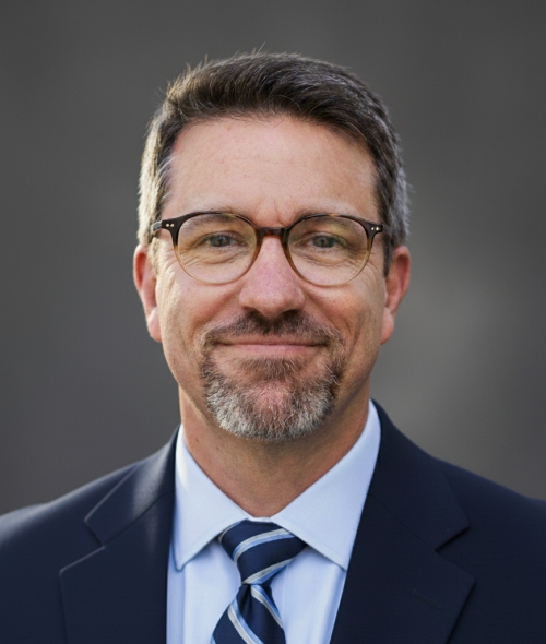 A man in a blue suit with glasses and a tie
