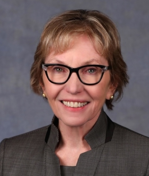 A white woman with blonde short hair and dark rimmed glasses