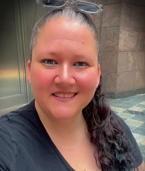 A caucasian woman with dark wavy hair in a ponytail