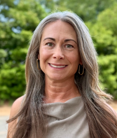 a woman with greying hair smiling outside