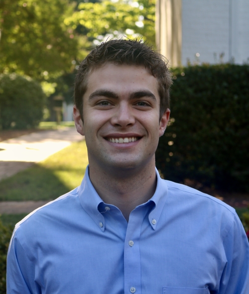Will smiling outdoors in a light blue button-down shirt with short brown hair.