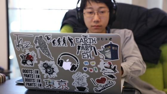 Student types at laptop while wearing headphones