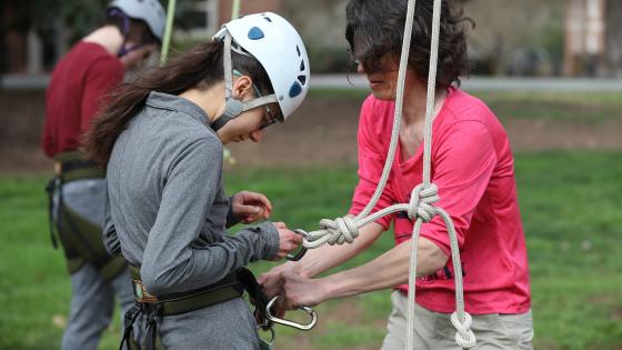 Linda helps student with harness fitting
