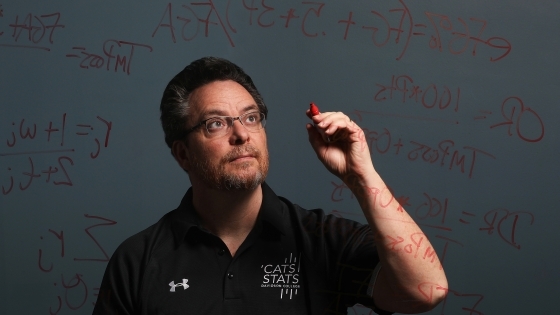 Tim Chartier writes math equations on a glass board