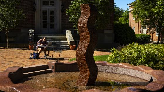 Student studying by art sculpture
