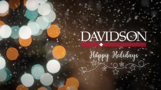 Davidson Logo and words "Happy Holidays" above a photo of some holiday lights and snow
