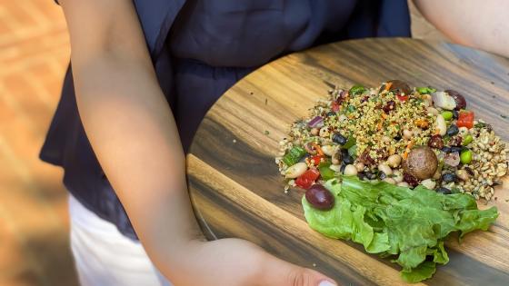 Student holds platter with plant-based meal with veggies and grains