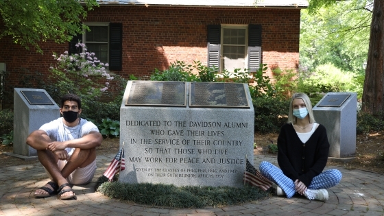 Students Gabe Jones ’24 and Charlotte Jenkins ’22 seated at campus WWII memorial