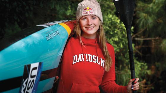 Evy Leibfarth Holding Kayak and Paddle in Davidson College Sweatshirt