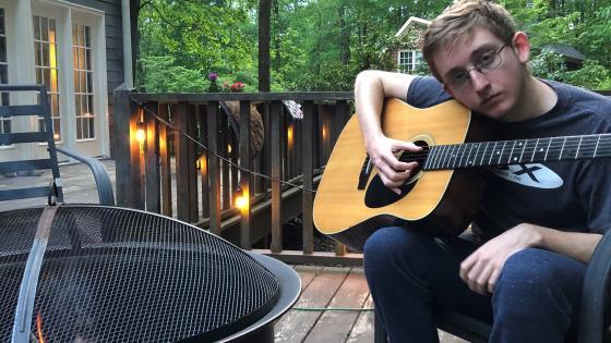 Davidson College music scholarship student Cooper Ray Oljeski '25 holds guitar on patio with firepit