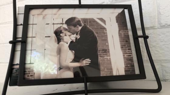 A picture frame of Andrea and David sharing a kiss in their wedding clothes 