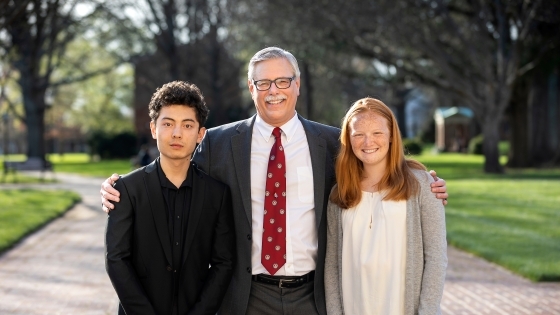 Prof. Emeritus Rich Neidinger outside with two student inductees on his left and right