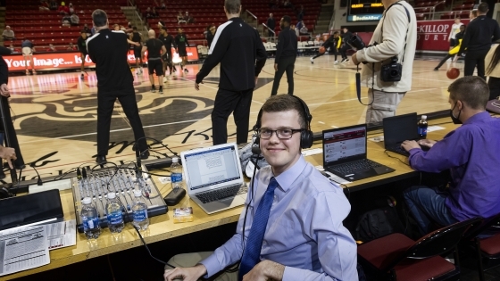 Sam Goldfarb at a basketball game with a headset and laptop on the sidelines