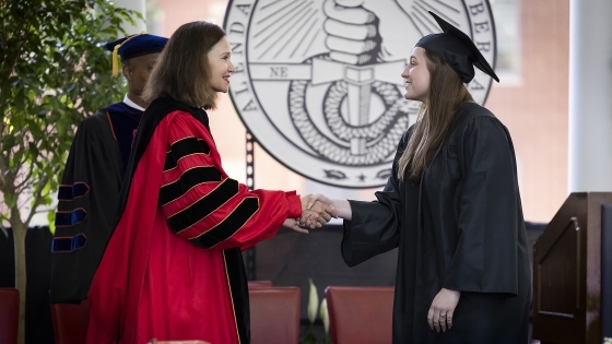 President Quillen shaking student's hand on stage at Class of 2022 Commencement