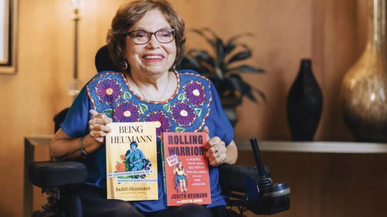 Judy Heumann holding two books