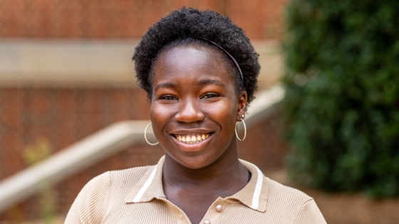 student smiling at camera wearing a beige polo