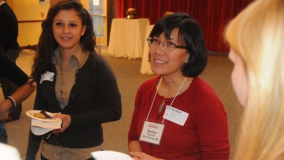 A woman speaks with two young students