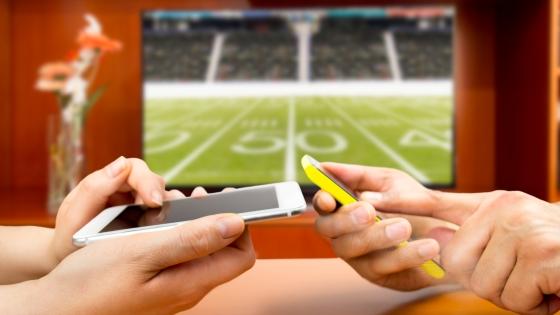 Two people on cell phones in front of football game