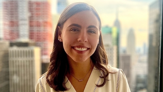 a young white woman smiles in front of a NYC skyline