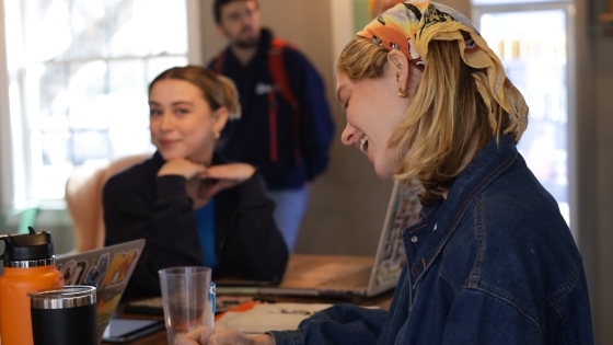 two students smile while working in a coffee shop