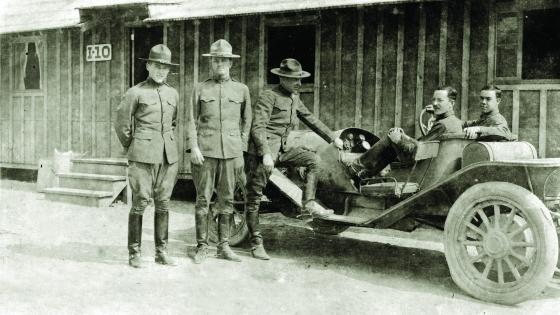 a group of soldiers in World War I uniforms stand around a car