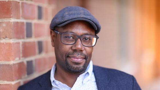 a middle aged Black man wearing glasses, hat and collared shirt with jacket