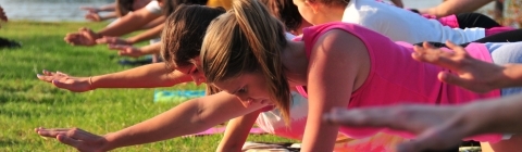 Students take yoga positions on mats laid out on the grass of Lake Campus