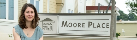 Elizabeth Welliver '16 sits on pavement next to the Moore Place community organization sign