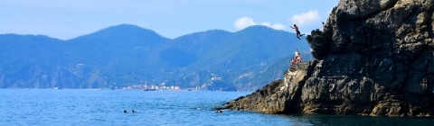 Ocean meets a cliff where a boy cliffdives in Sienna