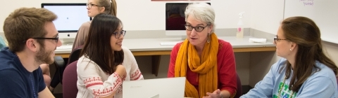 Prof. Munger sits at a round table with three students in her lab