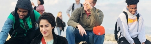 Four students sit on rocks at the Acropolis laughing