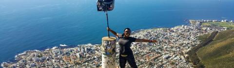 Jaela Cabrera McDonald '18 poses atop a boulder in Cape Town, showing the ocean and the city behind her