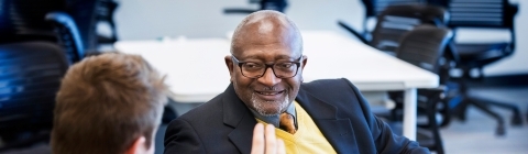 Robert Bullars smiles while a student sitting next to him discusses economics