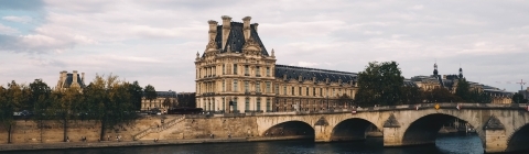 River meets a bridge with a french architecture building in the background