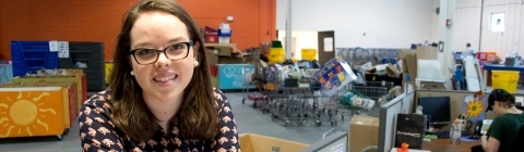 Student at internship leans over a counter with her workplace in the background
