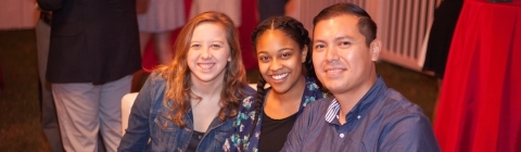 Three alumni sit together at a homecoming event