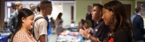 Recruiter talks to student at a booth at job fair