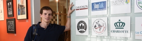 Student at his fellowship leans on glass wall with company logos