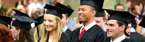 Students in cap and gown stand in a row