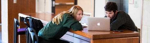 Students sits in chair while using laptop