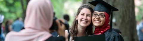 Friends hold diploma while family member takes photo of them