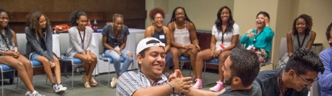 Two students sit next to each other during a team building game surrounded by other students