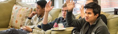 Students raise their hands while sitting on the couch at an event at Spencer Weinstein Center