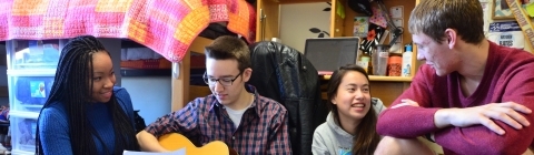Students hang out in a dorm playing the guitar