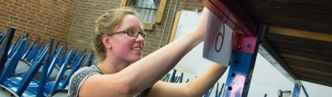 Student in community-based learning course helps organize a warehouse with a mathematical algorithm and hangs signs up in warehouse