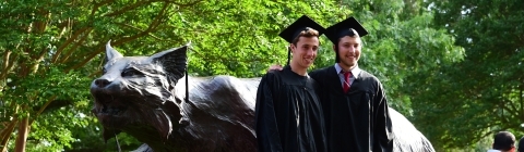 Two graduates stand near the Wildcat
