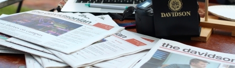 The Davidsonian copies on a table with a laptop and Davidson gear